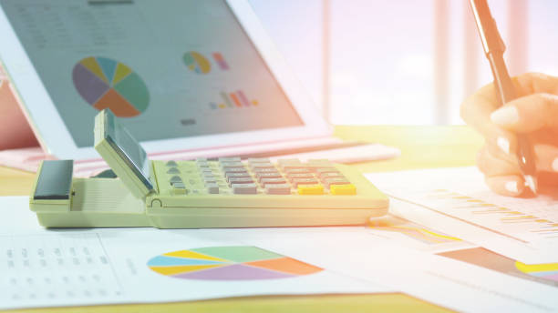 istock Office desk with female hands, graphs, calculator and pc device 917478898