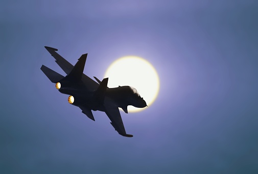 Jet fighter flying under sunlight