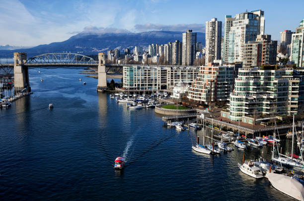 False Creek in winter, Vancouver, Canada False Creek in winter on a sunny afternoon, a ferry with canadian flag canopy passing by. false creek stock pictures, royalty-free photos & images