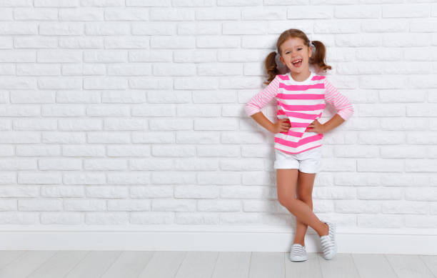 a happy child girl near an empty brick wall