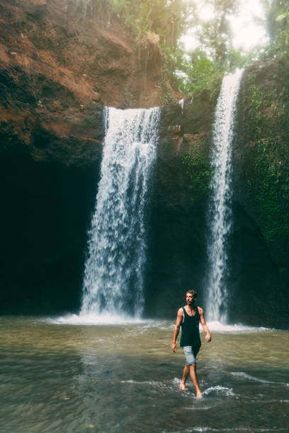 istock Man walking near  Tibumana waterfall in Bali 917511522