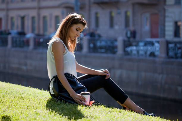 istock Female sitting on the grass drinking coffee in a cardboard Cup 917518700