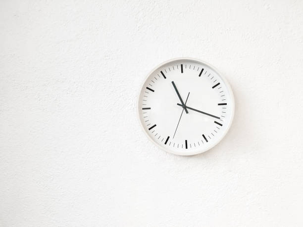 Simple modern round clock on white wall stock photo