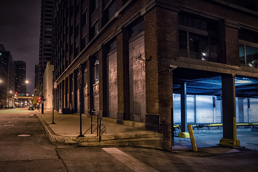 Dark city downtown street corner with an industrial warehouse loading dock at night.