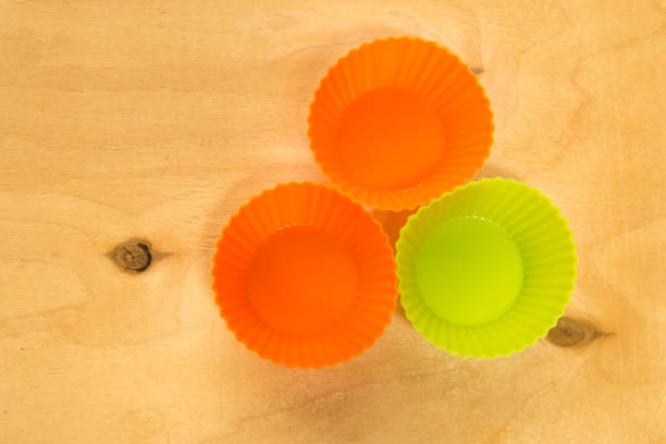 istock Orange and light green silicone baking cups for muffins or cupcakes on solid wood background. Top view. 917542070