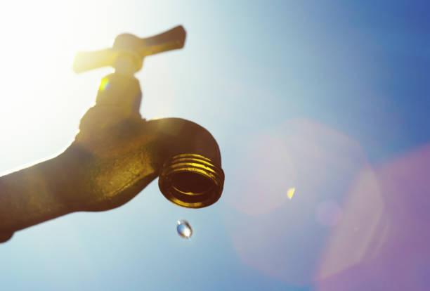 Last drop of water, symbolizing drought A single droplet falls from a faucet, symbolizing water scarcity or drought. water crisis stock pictures, royalty-free photos & images