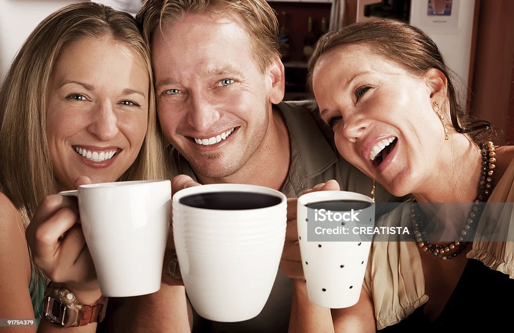 Three friends having fun while toasting with coffee Three friends in a coffee house toasting with their cups Adult Stock Photo