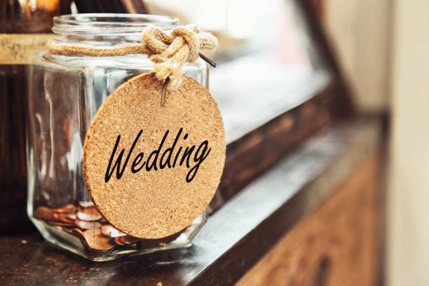 vintage retro glass jar with hemp rope tie wedding tag and few coins inside on wood counter concept of saving money for wedding - coin cheap jar currency imagens e fotografias de stock