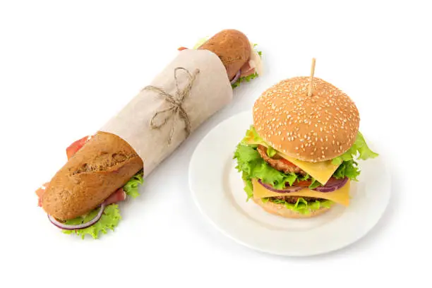 Photo of Double burger on a plate and wrapped sandwich to take away on white background with soft shadows