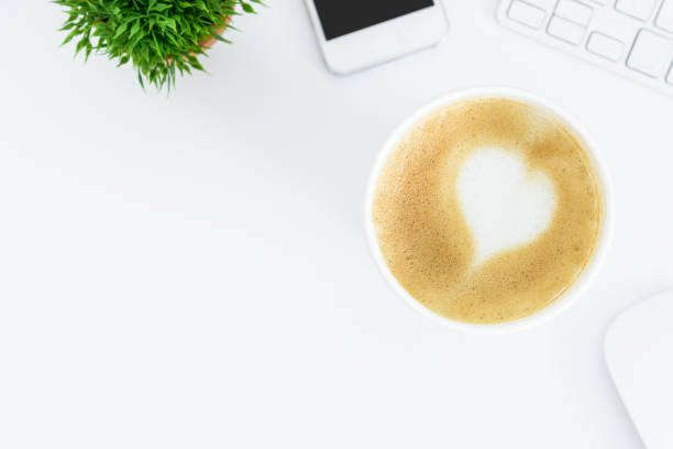 istock A latte coffee with art heart milk on the white desk table from top view and copy space. Flat lay with desk, business and valentine concept. 917555344