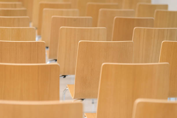 istock Many empty wooden chairs set neat rows in conference room 917565886