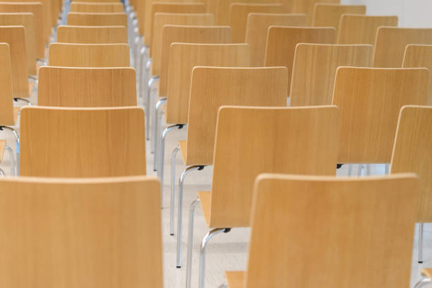 istock Many empty wooden chairs set neat rows in conference room 917565976