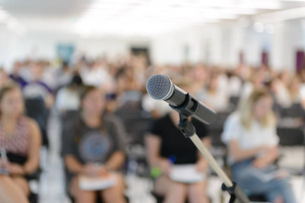 istock Microphone over abstract blurred of attendee in seminar room 917566080