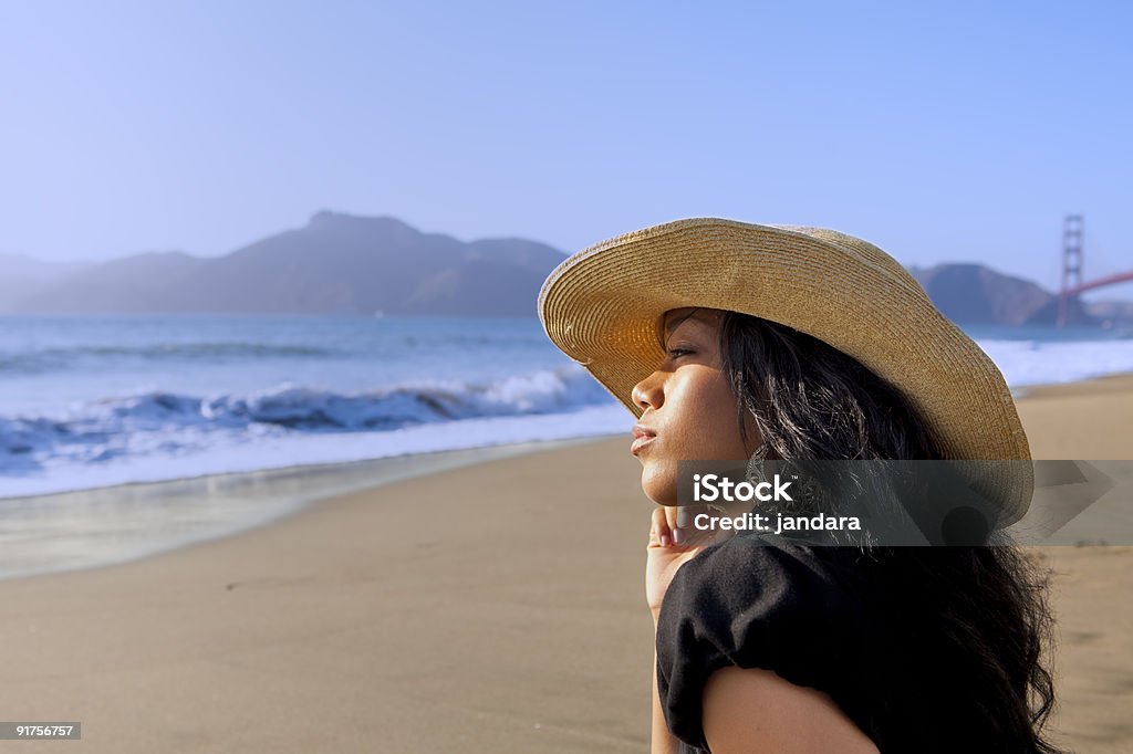 Giovane donna sulla spiaggia indossando un cappello - Foto stock royalty-free di Close-up