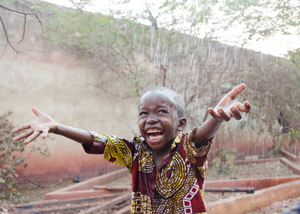 doux petit garçon africain sous la pluie au mali (afrique) - africa child village smiling photos et images de collection