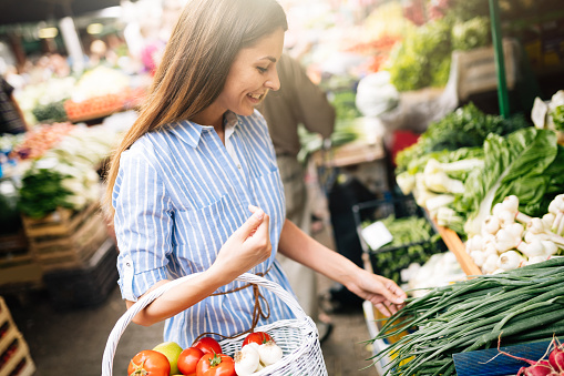 Picture of beautiful woman at marketplace buying vegetables