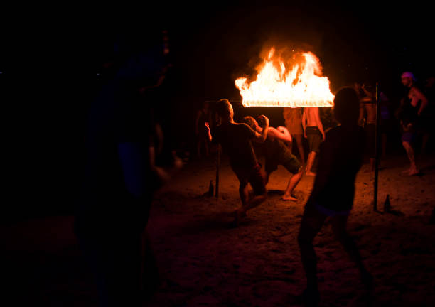 Koh Tao, Thailand - December 10, 2017: Young people partying and dancing limbo at fire show on the beach