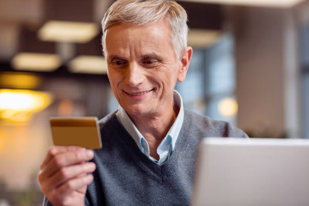 istock Gay mature man reading his card number 917577816