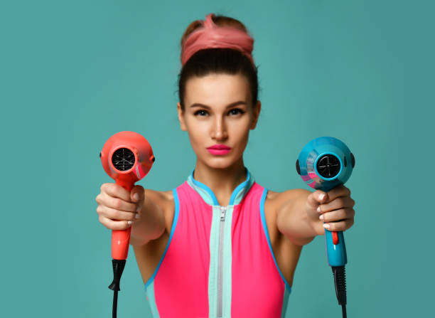 Happy young brunette woman with hair dryer on blue mint background Happy young brunette woman with hair dryer on blue mint background. Hair style beauty concept fen photos stock pictures, royalty-free photos & images
