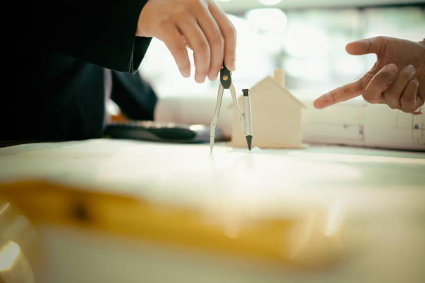 istock engineers pointing to building on blueprint and using laptop to drawing design building Project in office, construction concept. Engineer concept 917587204