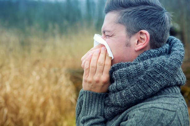 istock blond man outdoors blowing his nose 917587250