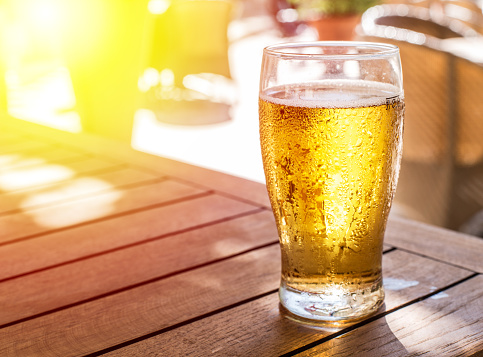 Glass of light beer on the wooden table.