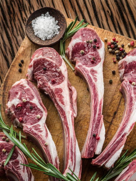 istock Raw lamb chops with garlic and herbs on the old wooden table. 917589998