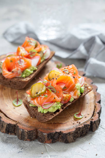 istock Smorrebrod with salmon on rye bread with vegetables and herbs 917590900