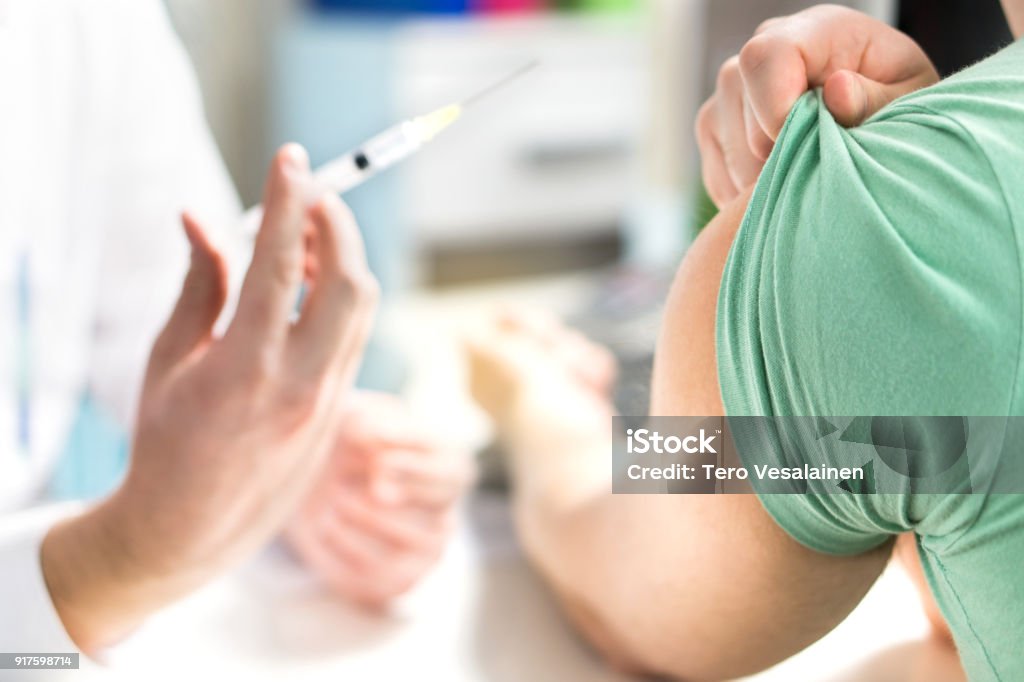 Doctor giving patient vaccine, flu or influenza shot or taking blood test with needle. Nurse with injection or syringe. Doctor giving patient vaccine, flu or influenza shot or taking blood test with needle. Nurse with injection or syringe. Medicine, insulin or vaccination. Hospital office room. Vaccination Stock Photo