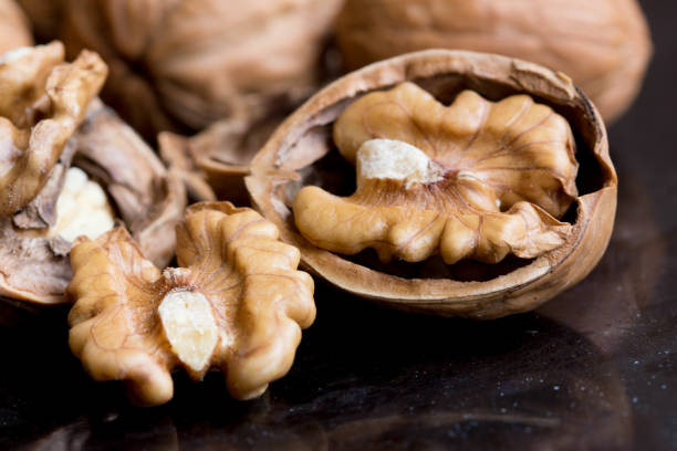 macro of walnuts on black background - vegan food still life horizontal image imagens e fotografias de stock