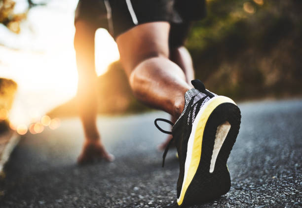 Take that step towards a healthier you Low angle shot of a man out exercising on a tarmac road starting block stock pictures, royalty-free photos & images