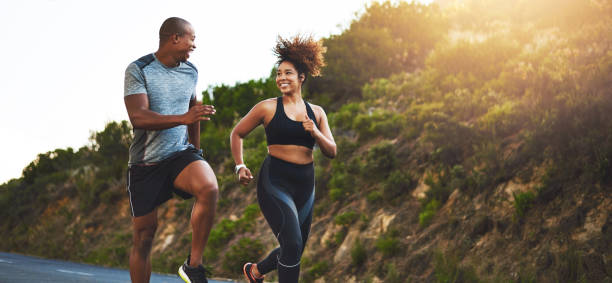Be strong, you never know who you’re inspiring Shot of a young couple out running together healthy lifestyle women outdoors athlete stock pictures, royalty-free photos & images