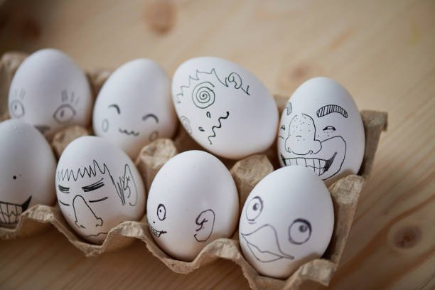 Close-up of egg carton filled with creative Easter eggs with funny faces on table