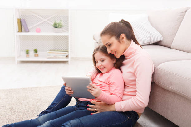 istock Little girl and her mom using a tablet at home 917606036