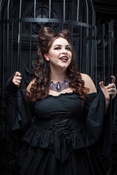 istock Beautiful plump woman is standing by the black cage. 917606054