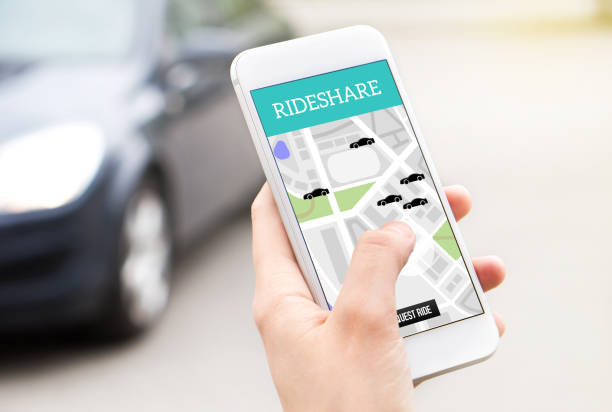 istock Ride share taxi service on smartphone screen. Online rideshare app and carpool mobile application. Woman holding phone with a car in the background. 917611362