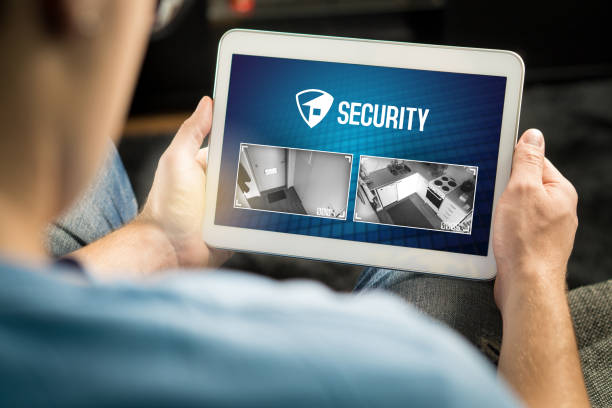 Man using home security system and application in tablet. Watching protection camera live footage inside a house or apartment. Man using home security system and application in tablet. Watching protection camera live footage inside a house or apartment. Smart cctv and safety app. webcam view man stock pictures, royalty-free photos & images