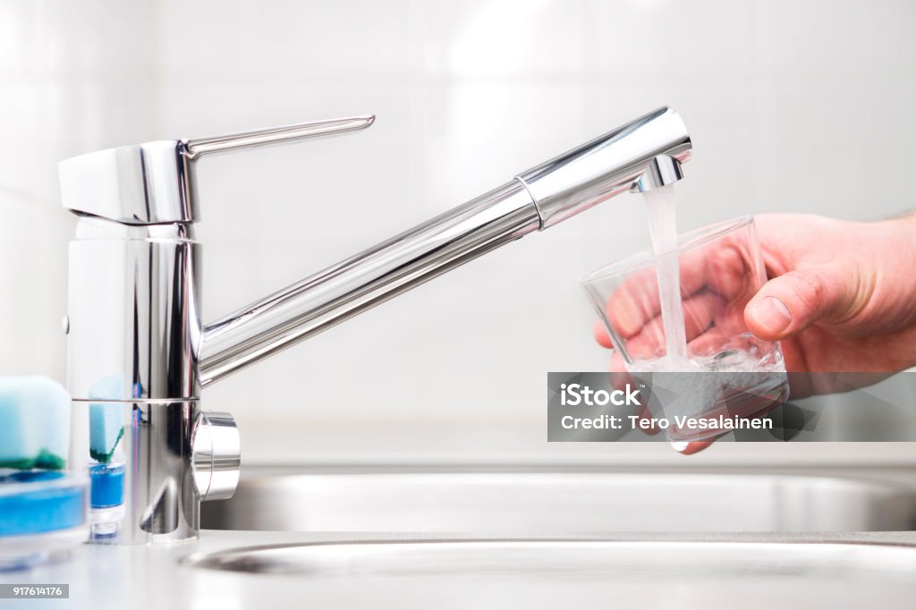 Filling glass with tap water. Modern faucet and sink in home kitchen. Filling glass with tap water. Modern faucet and sink in home kitchen. Man pouring fresh drink to cup. Water Stock Photo