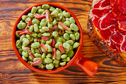 Tapas lima beans with iberico ham from Spain on wood