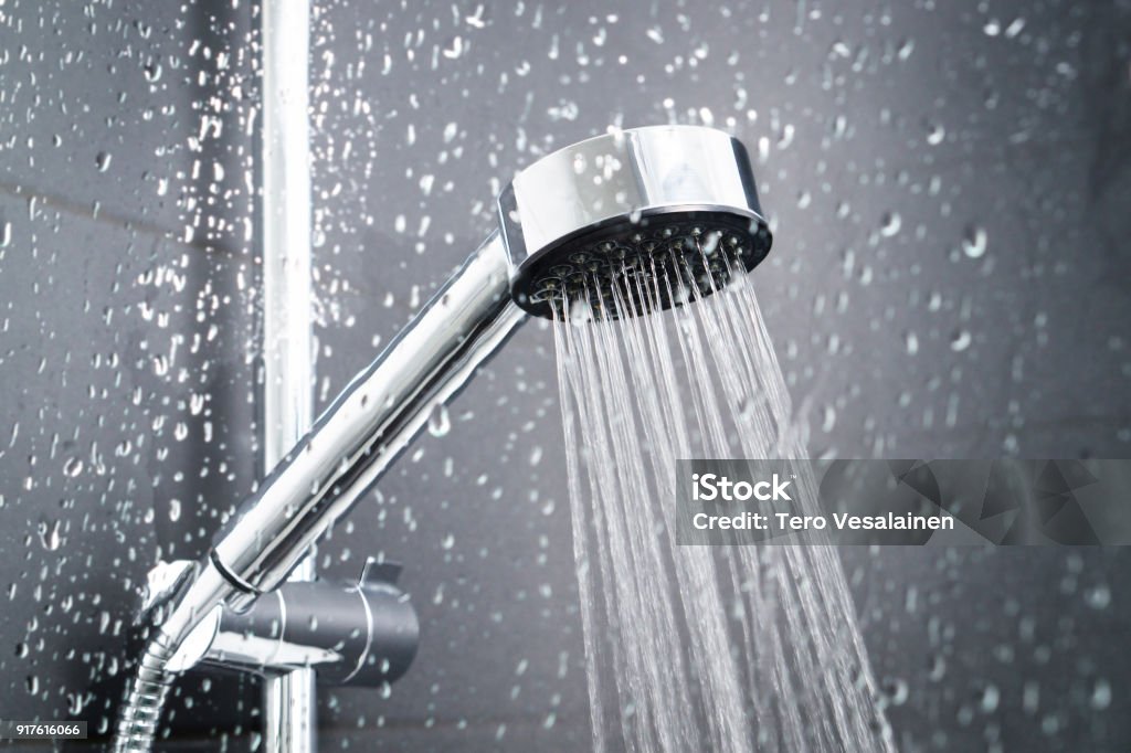 Fresh shower behind wet glass window with water drops splashing. Fresh shower behind wet glass window with water drops splashing. Water running from shower head and faucet in modern bathroom. Shower Stock Photo