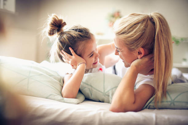 istock Mother and daughter lying on a bed looking etch other. 917619806