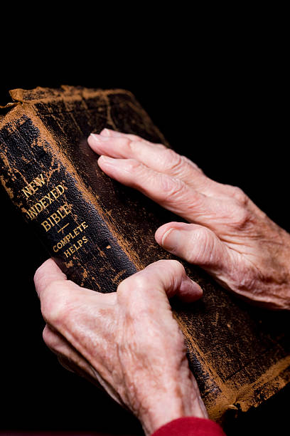 istock Weatherd Hands Clasping an Old Bible 91762406