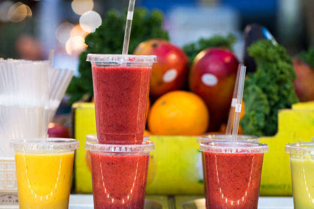 крупным планом свежих фруктовых смузи и соков подряд для продажи на вегетарианском рынке стойло - smoothie fruit orange juice стоковые фото и изображения