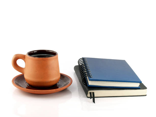 istock brown pottery coffee cup with saucer and two closed diary books isolated on white background 917624976