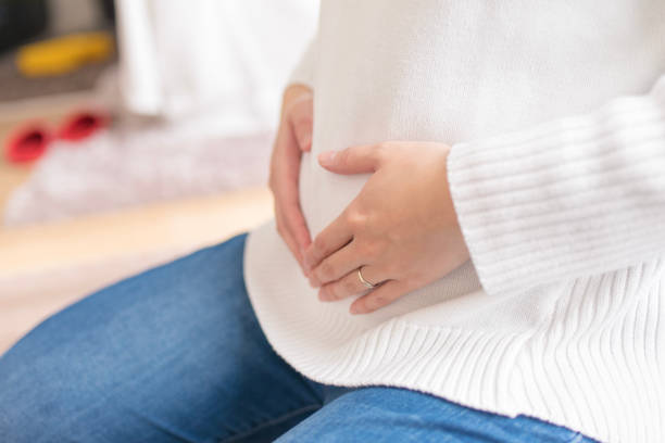 pregnant woman touching abdomen - abdomen women loving human hand imagens e fotografias de stock