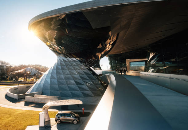 Munich, Germany - December 7, 2017: BMW i3 electric car standing at a charging station at BMW Welt World of BWM with exhibition and museum buildings at sunset with sunlight. Focus on background