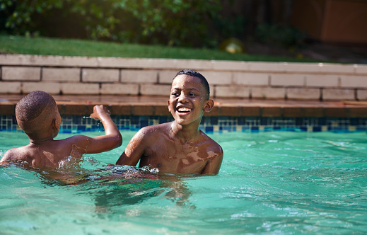 Shot of two young boys having fun together in a swimming pool