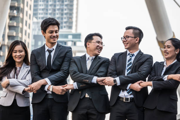 istock Successful Asian business team celebrating their triumph with holding hands together. Teamwork and success concept 917634016