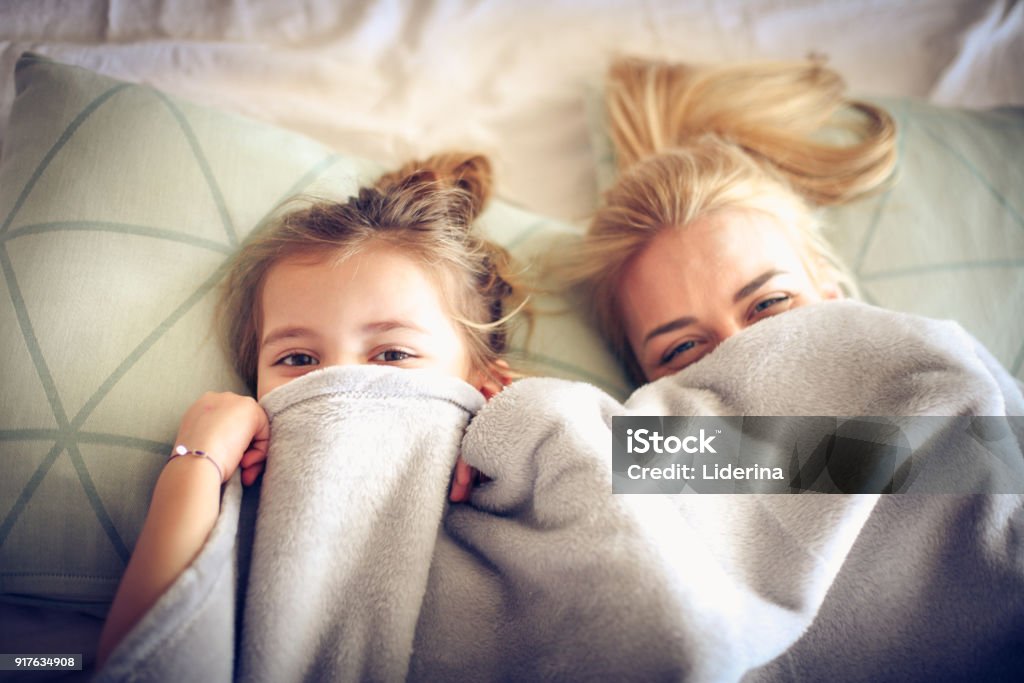 Porträt-Mutter und Tochter verstecken sich unter der Decke auf einem Bett. - Lizenzfrei Bett Stock-Foto