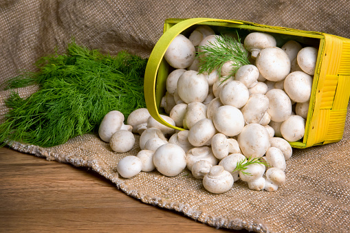 Champignons in a basket, along with vegetables on the table. close-up